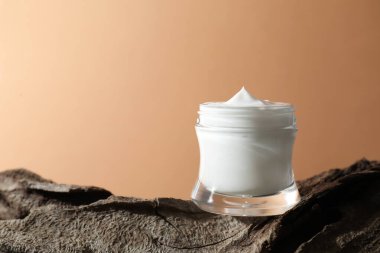 Bej arka planda yüz kreminin şık bir sunumu. Metin için boşluk