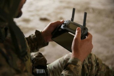 Military mission. Soldier in uniform with drone controller inside abandoned building, closeup