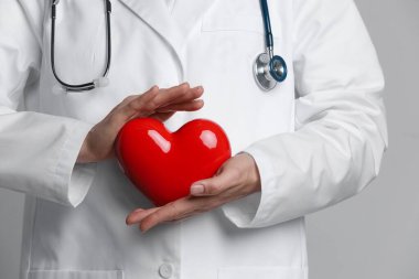 Gri arka planda kırmızı kalpli doktor, yakın plan.