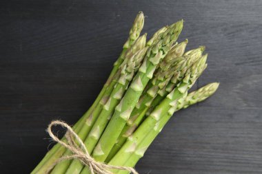 Gri ahşap masada taze yeşil kuşkonmaz sapları var.