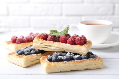 Böğürtlenli börek ve beyaz ahşap masada çay, yakın plan.