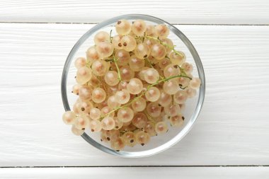 Beyaz ahşap masada kasede taze üzümlü üzümler.