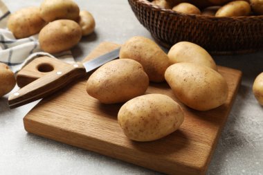 Bir sürü taze patates, yemek ve bıçak gri masada, yakın plan.