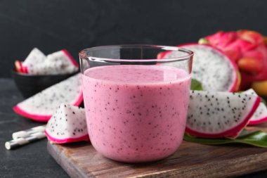 Lezzetli pitahaya smoothie ve siyah masada taze meyveler, yakın plan.