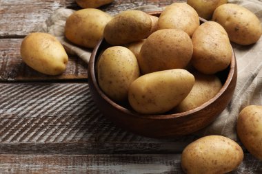 Manzaranın üstünde, ahşap masada bir sürü taze patates var.