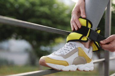 Kadın dışarıda ayak bileği ağırlığı takıyor, yakın plan. Metin için boşluk