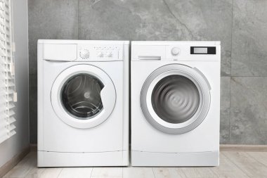 Çamaşır odasında duvarın yanında iki çamaşır makinesi var.