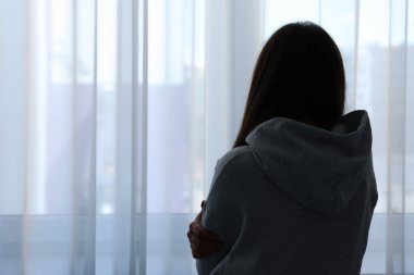 Yalnızlık kavramı. Evinin penceresinin yanında üzgün bir kadın var. Metin için boşluk