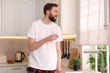 Sabahları mutfakta bir bardak suyla mutlu genç bir adam.