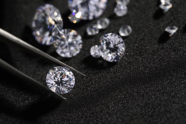 Güzel parlak elmasları olan siyah kumaşlı cımbızlar, yakın plan.