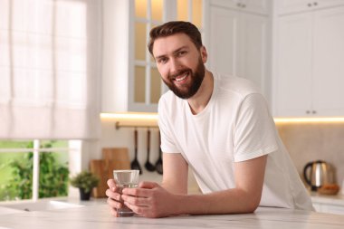 Sabahları mutfakta bir bardak suyla mutlu genç bir adam.