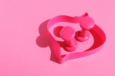 Dambıllar ve jimnastik bandı pembe arka planda. Metin için boşluk