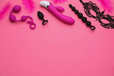 Pembe arka planda seks oyuncakları, tüy ve siyah dantel maske. Metin için boşluk