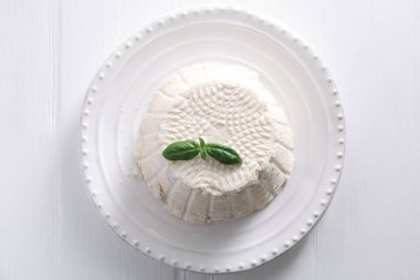 Taze ricotta (krem peynir) üzerine fesleğen, beyaz ahşap masa, üst manzara