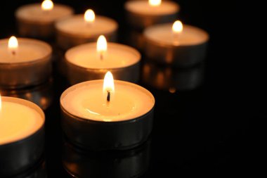 Siyah arkaplanda birçok yanan gece lambası mumu, yakın plan