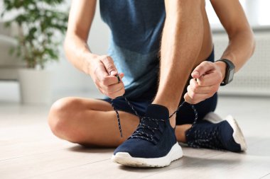 Spor ayakkabısının bağcığını bağlayan adam, yakın plan.