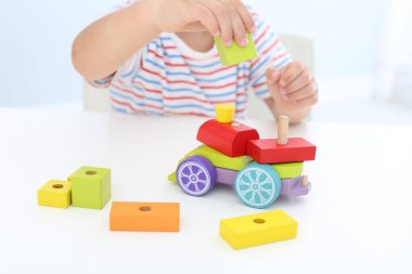 Küçük çocuk beyaz masada oyuncakla oynuyor, yakın plan.