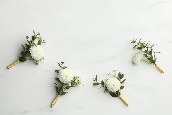 stock image Small stylish boutonnieres on white marble table, flat lay. Space for text