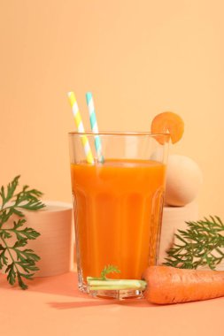 Bardakta taze havuç suyu ve mercan zemininde sebze.