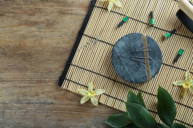 Flat lay composition with acupuncture needles on wooden table. Space for text clipart