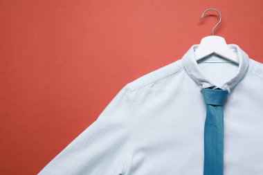 Mercan arka planda beyaz gömlekli ve turkuaz kravatlı askı, üst manzara. Metin için boşluk
