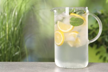 Açık havada gri masada naneli sürahi içinde taze limonata, mesaj için yer.