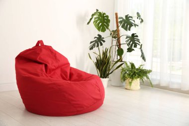 Odadaki ışık duvarının yanındaki kırmızı fasulye koltuğu. Metin için boşluk