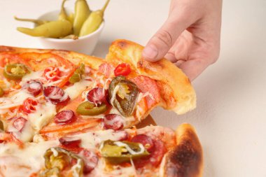 Woman taking piece of delicious pizza Diablo at white textured table, closeup clipart