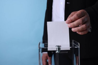Adam oyunu açık mavi arka plana karşı sandığa koyuyor, yakın plan. Metin için boşluk