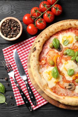 Siyah ahşap masada servis edilen lezzetli vejetaryen pizza.