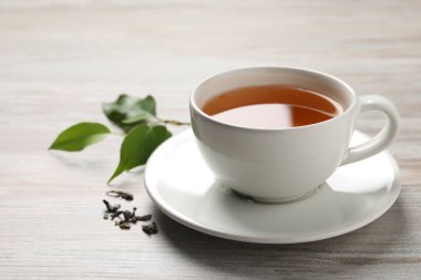 Yeşil çayı fincanda tazeleyen ve gri ahşap masada yapraklar, yakın plan