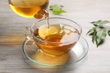 Gri ahşap masada serinletici yeşil çayı fincana dök, kapat.