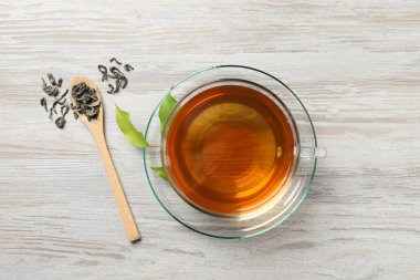 Fincanda yeşil çay, kaşık ve yapraklar hafif ahşap masa, düz uzanmış
