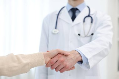 Doktor klinikte hastayla el sıkışıyor.