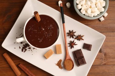 Lezzetli eritilmiş çikolata, marşmelov, şeker ve baharatlar ahşap masada, düz yerde.