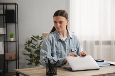 Ahşap masada dizüstü bilgisayarlı utangaç bir kadın.
