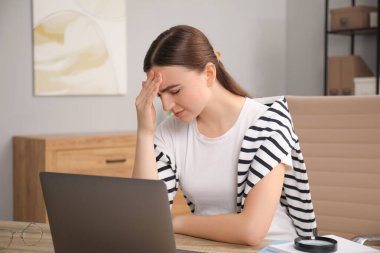 Ahşap masada dizüstü bilgisayarlı utangaç bir kadın.