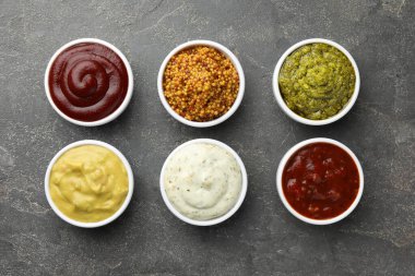 Gri masadaki kaselerde bir sürü farklı sos var.