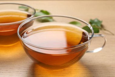 Ahşap masadaki fincanlarda taze yeşil çay, yakın plan.