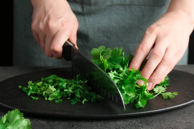 Gri desenli masada taze kişniş kesen kadın, yakın plan.