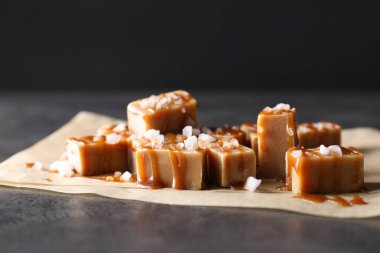 Lezzetli şekerler, karamel sosu ve tuz gri masada, yakın plan.