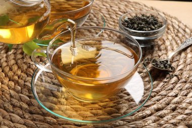 Masadaki fincana serinletici yeşil çay dolduruyorum, yakın plan.