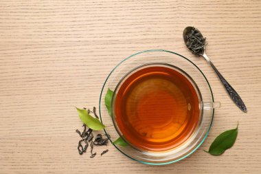 Yeşil çayı fincanda, kaşıkta ve yaprakları ahşap masada, düz yerde serinletiyor. Metin için boşluk