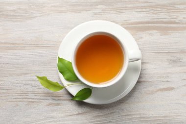 Yeşil çayı fincanda tazelemek ve açık ahşap masa üzerinde yapraklar, üst manzara