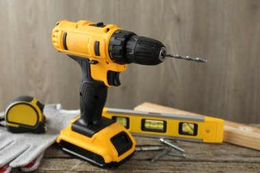 Kablosuz elektrik matkabı, eldivenler, bitler, mezura ve ahşap masadaki bina seviyesi