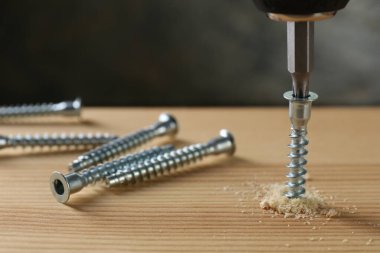 Vidaları tahta tahtaya vidalamak gri arka plan, yakın çekim