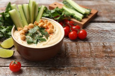 Lezzetli humus, kase içinde nohut ve ahşap masada taze ürünler, yakın plan. Metin için boşluk