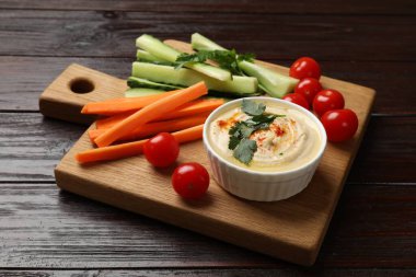 Lezzetli ev yapımı humus ve siyah ahşap masada farklı sebzeler.