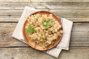 Taze üzümlü üzümler ve yeşil yapraklar ahşap masada, üst tarafta.