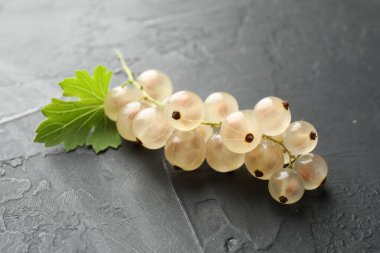 Gri desenli masada taze üzümler ve yeşil yaprak, yakın plan.